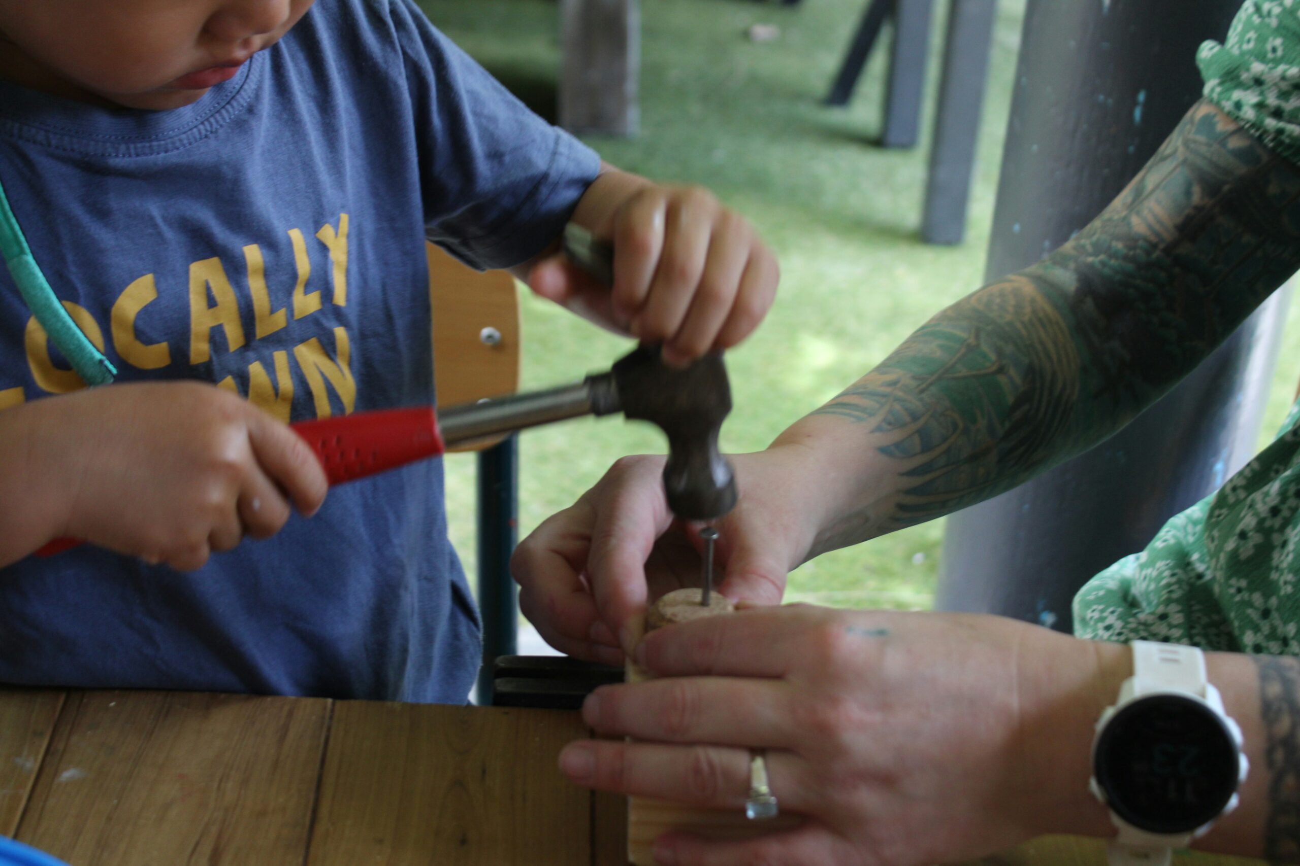 a woman and a child are working on a piece of wood